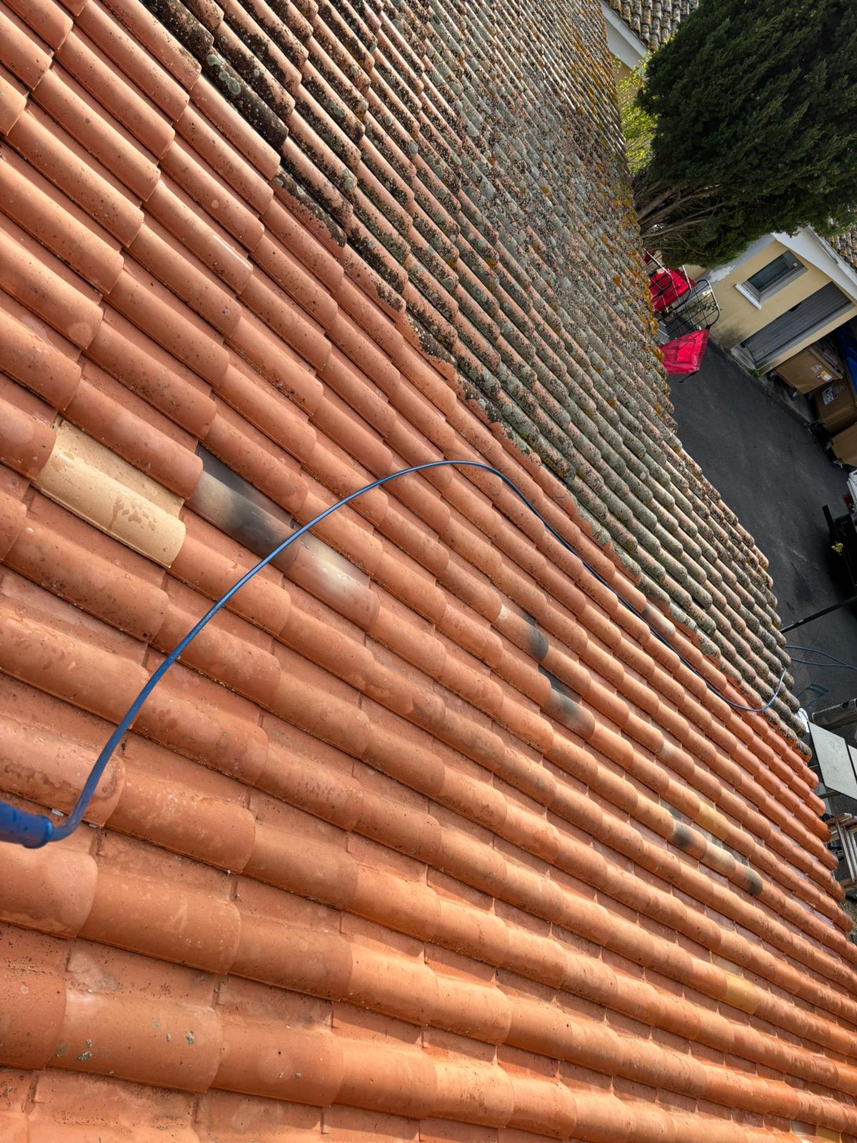 Toit en tuiles canal à moitié nettoyé : bas du toit propre et orange, haut encore gris de mousse