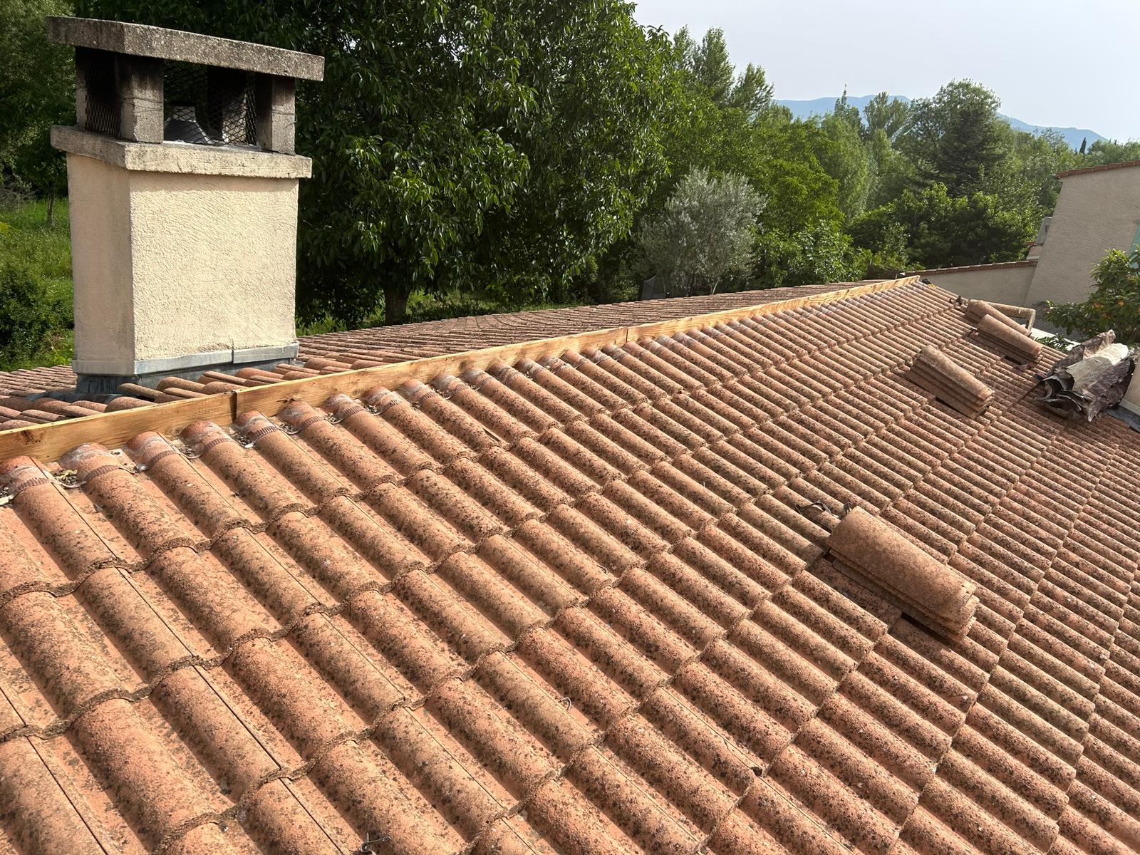 Faîtage déposé : une lisse en bois court le long du sommet du toit, les tuiles faîtières sont empilées à côté