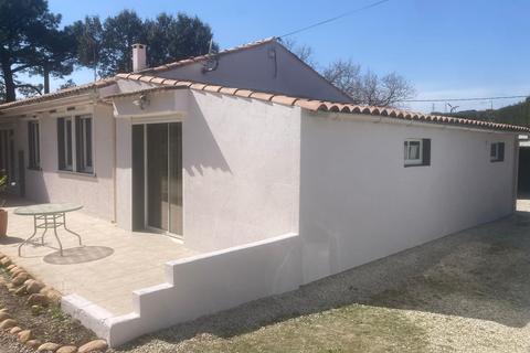 Maison de plain-pied aux murs fraîchement repeints en blanc, sous un toit de tuiles