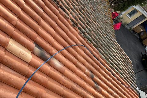 Toit en tuiles canal à moitié nettoyé : tuiles orange propres d’un côté, mousse grise de l’autre